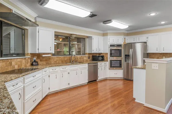 a kitchen with granite countertop white cabinets and stainless steel appliances
