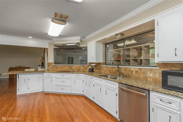 a kitchen with granite countertop a sink cabinets and stainless steel appliances