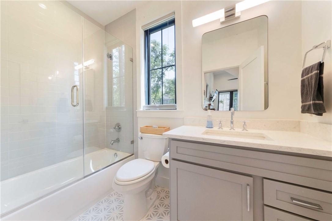 2002 East 9th Street, Unit 2 Austin, TX 78702 - Photo 14 of 32 A refined bathroom featuring a glass-enclosed shower over the tub and a spacious vanity with an integrated sink.
