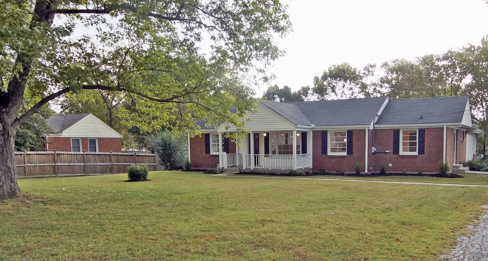 a front view of a house with a garden and trees