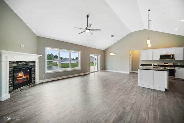 a view of an empty room with kitchen and a fireplace
