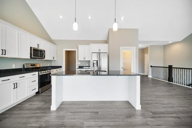 a large kitchen with cabinets wooden floor and stainless steel appliances