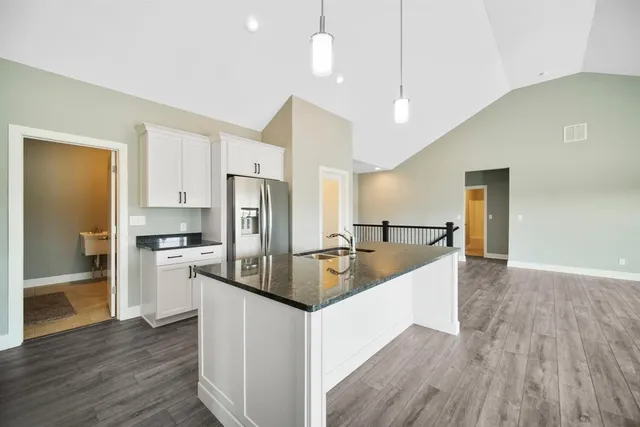 a large kitchen with a center island wooden floor stainless steel appliances and cabinets