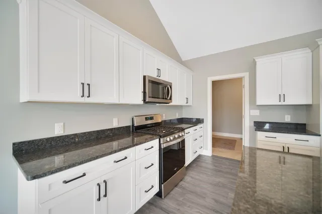 a kitchen with granite countertop a stove top oven sink and cabinets