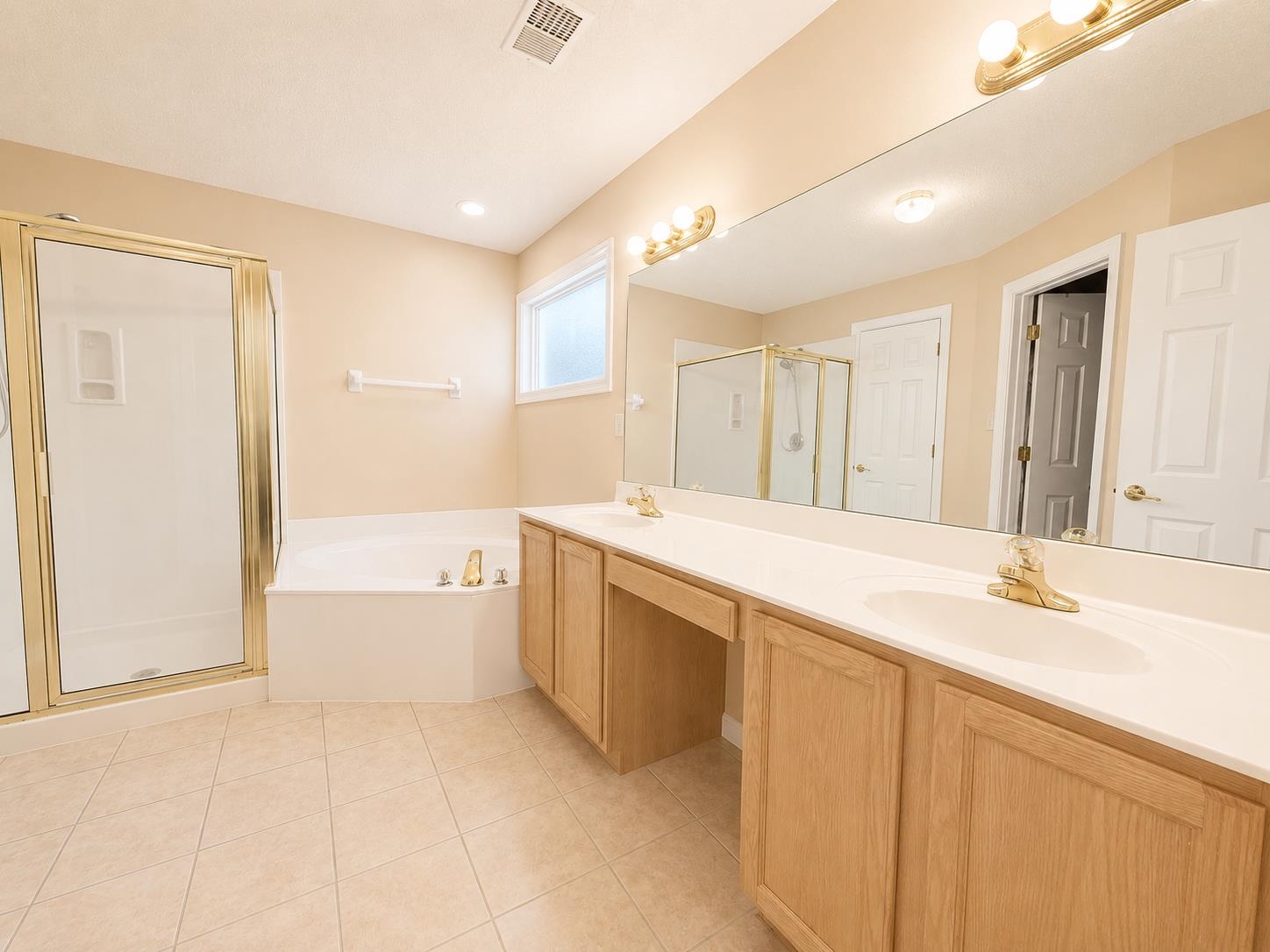 326 South Sanga Road Cordova, TN 38018 - Photo 20 of 32 Primary Bathroom featuring a dual vanity with light wood cabinetry, a large vanity mirror, a corner soaking tub, a stand-up shower with a glass enclosure, and tiled flooring