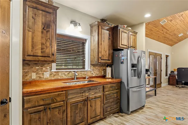 a large kitchen with a stove a sink dishwasher and a refrigerator with wooden floor