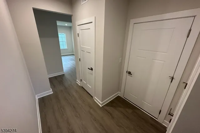 an empty room with wooden floor and a hallway