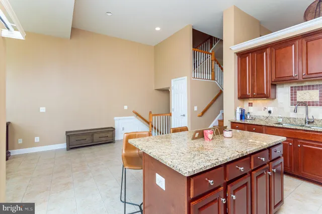 a kitchen with kitchen island granite countertop a sink and a refrigerator