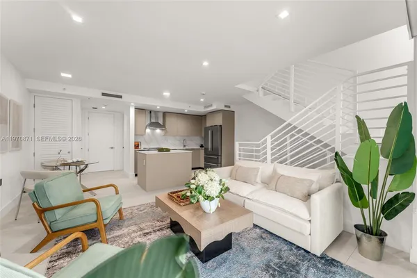 a living room with furniture kitchen view and a potted plant