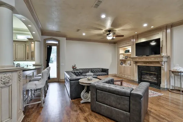 a living room with furniture a fireplace a flat screen tv and kitchen view
