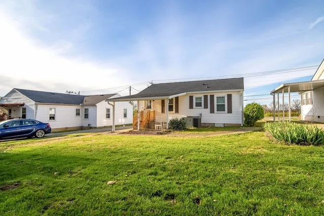 a view of a house with a big yard and large trees