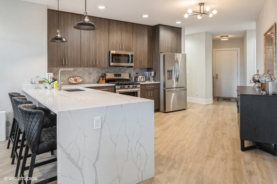3839 North Clark Street, Unit 304 Chicago, IL 60613 - Photo 5 of 7 a kitchen with a sink a microwave a refrigerator and cabinets