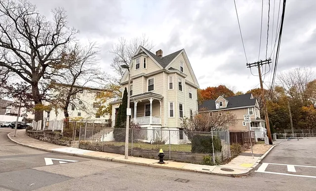 a view of a white house next to a road and iron fence
