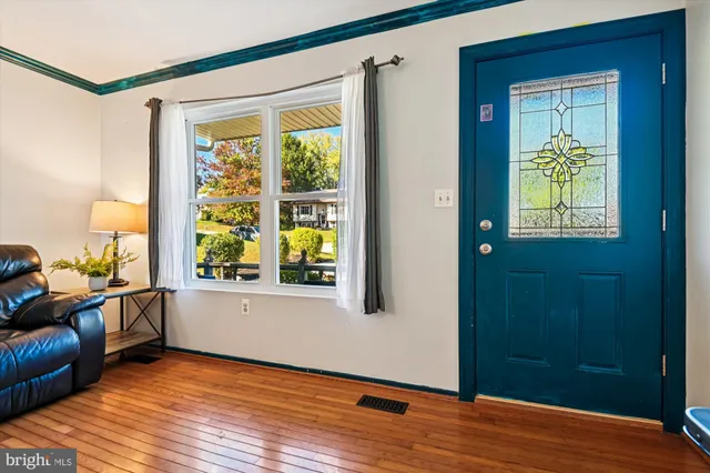 a view of an empty room with window and wooden floor