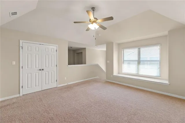 an empty room with chandelier fan and windows