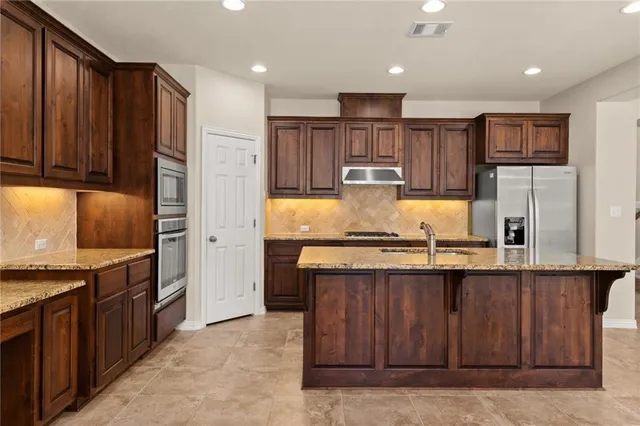 a kitchen with kitchen island granite countertop wooden cabinets and a refrigerator