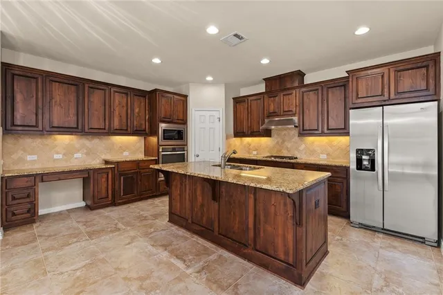 a kitchen with kitchen island granite countertop wooden cabinets stainless steel appliances and a granite counter tops
