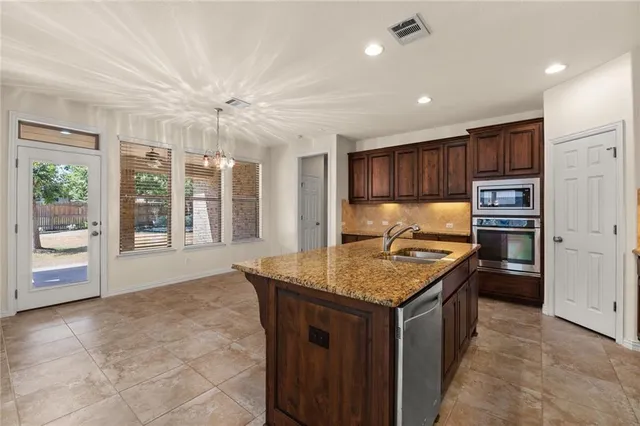 a kitchen with kitchen island granite countertop a stove top oven a sink with granite countertops and cabinets