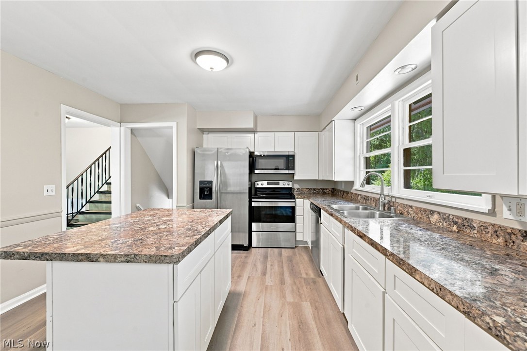 558 Garnette Road Akron, OH 44313 - Photo 7 of 31 Modern kitchen featuring white cabinetry, stone-finish countertops, stainless steel appliances, and wood-finish flooring