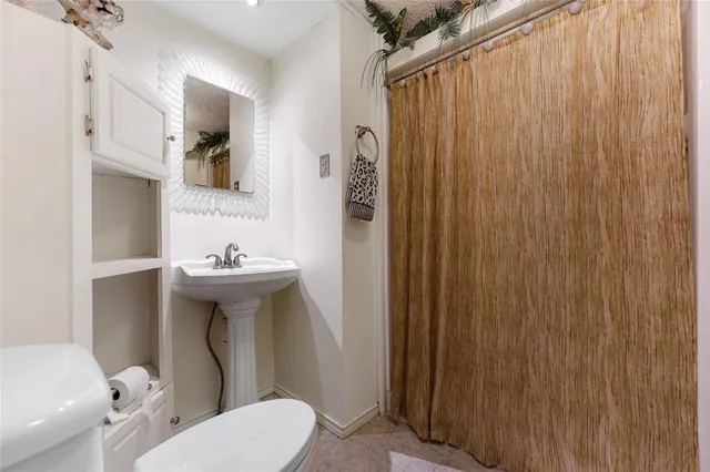 a bathroom with a sink a toilet and shower curtain