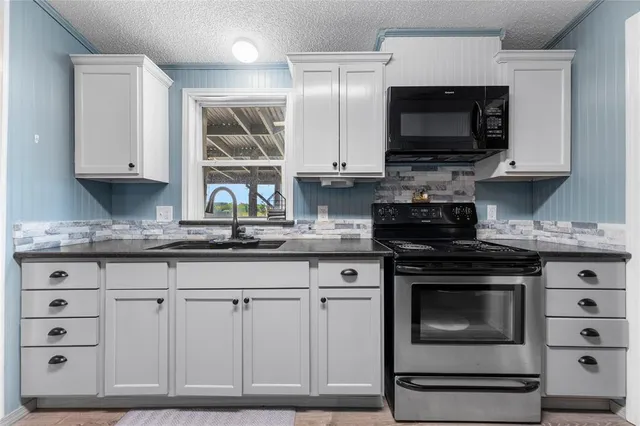 a kitchen with granite countertop a stove a microwave a sink and cabinets