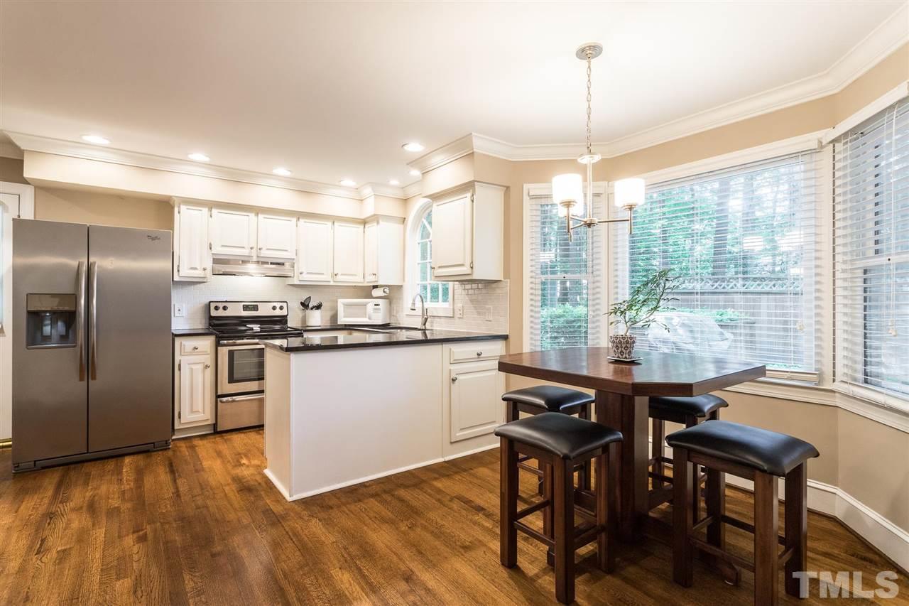 1025 Sawmill Road Raleigh, NC 27615 - Photo 10 of 25 a kitchen with stainless steel appliances granite countertop a stove a refrigerator a sink a dining table and chairs with wooden floor