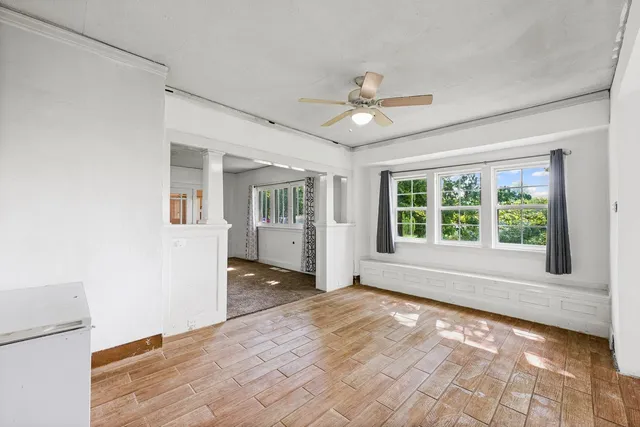 a view of an empty room with a window and wooden floor
