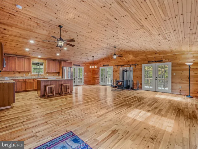 a view of an empty room with wooden floor and a kitchen