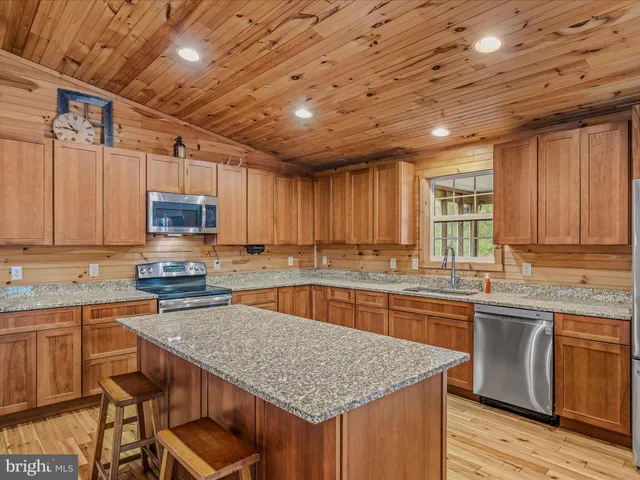 a kitchen with kitchen island granite countertop a sink stove and refrigerator