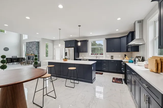 a kitchen with stainless steel appliances kitchen island granite countertop a sink a stove a refrigerator cabinets and chairs