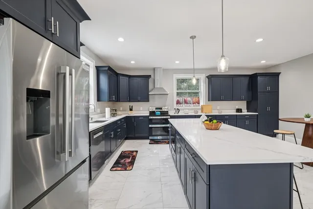 a large kitchen with stainless steel appliances kitchen island granite countertop a refrigerator a sink a stove and a cabinets