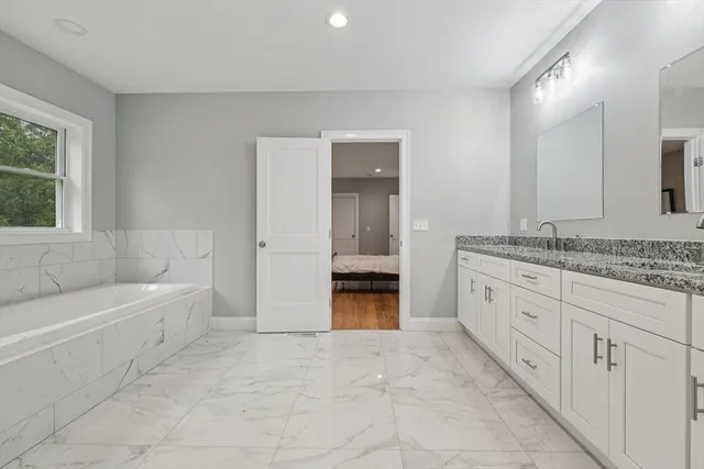 a bathroom with a granite countertop sink a mirror and a bathtub