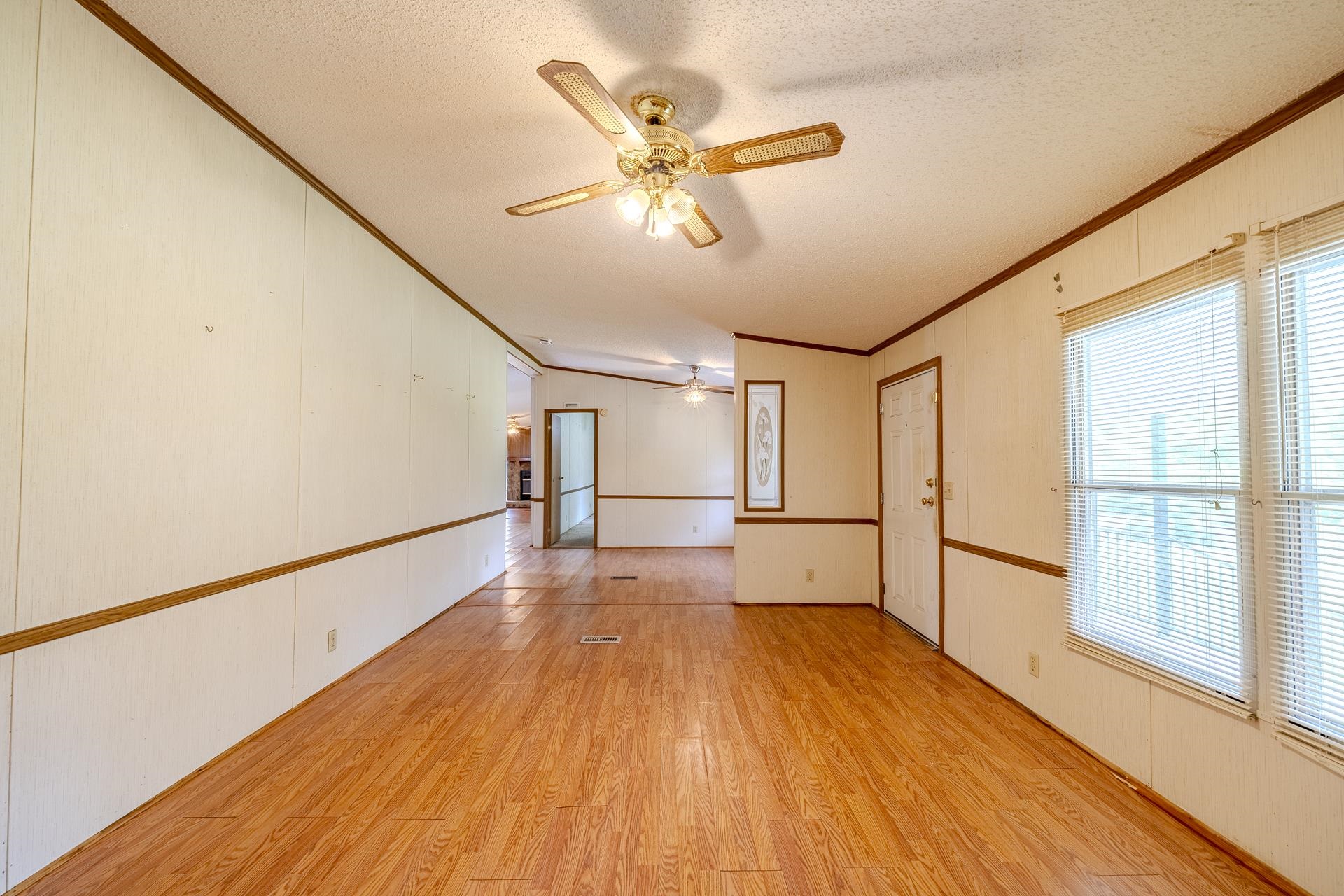 859 Old Morris Chapel Road Adamsville, TN 38310 - Photo 15 of 39 Expansive interior space featuring wood-finish flooring, white paneling with brown trim, and multiple windows with blinds