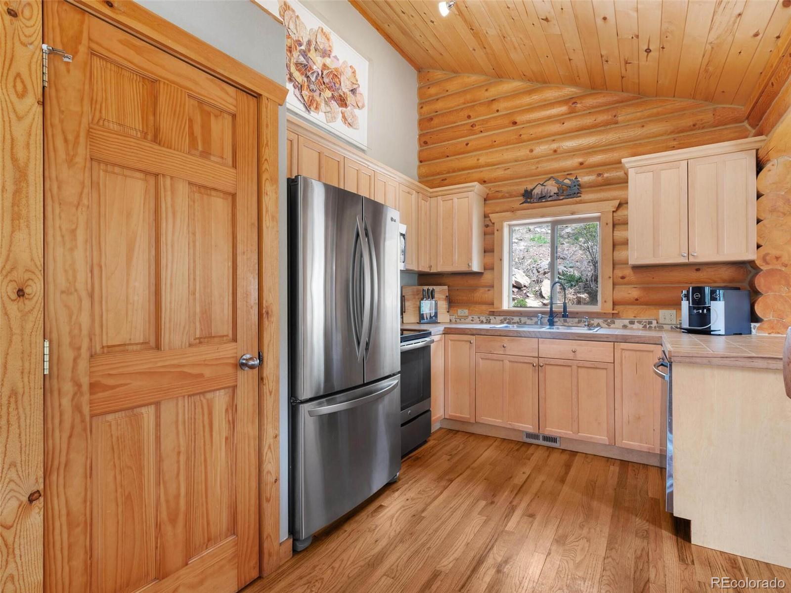 603 Old State Road Bailey, CO 80421 - Photo 12 of 40 a kitchen with a refrigerator a sink and dishwasher with wooden floor