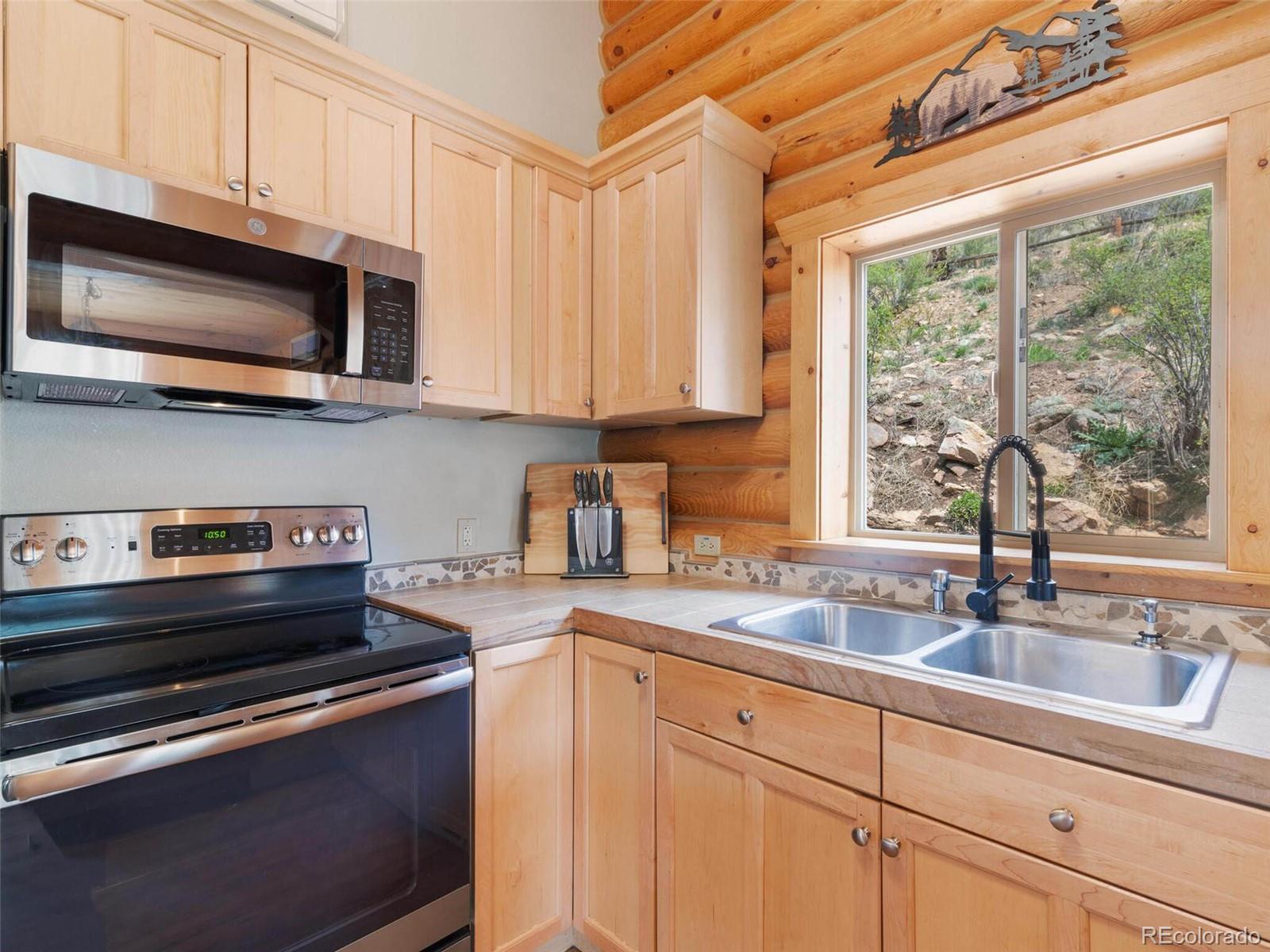 603 Old State Road Bailey, CO 80421 - Photo 14 of 40 a kitchen with stainless steel appliances granite countertop a sink a stove and a microwave