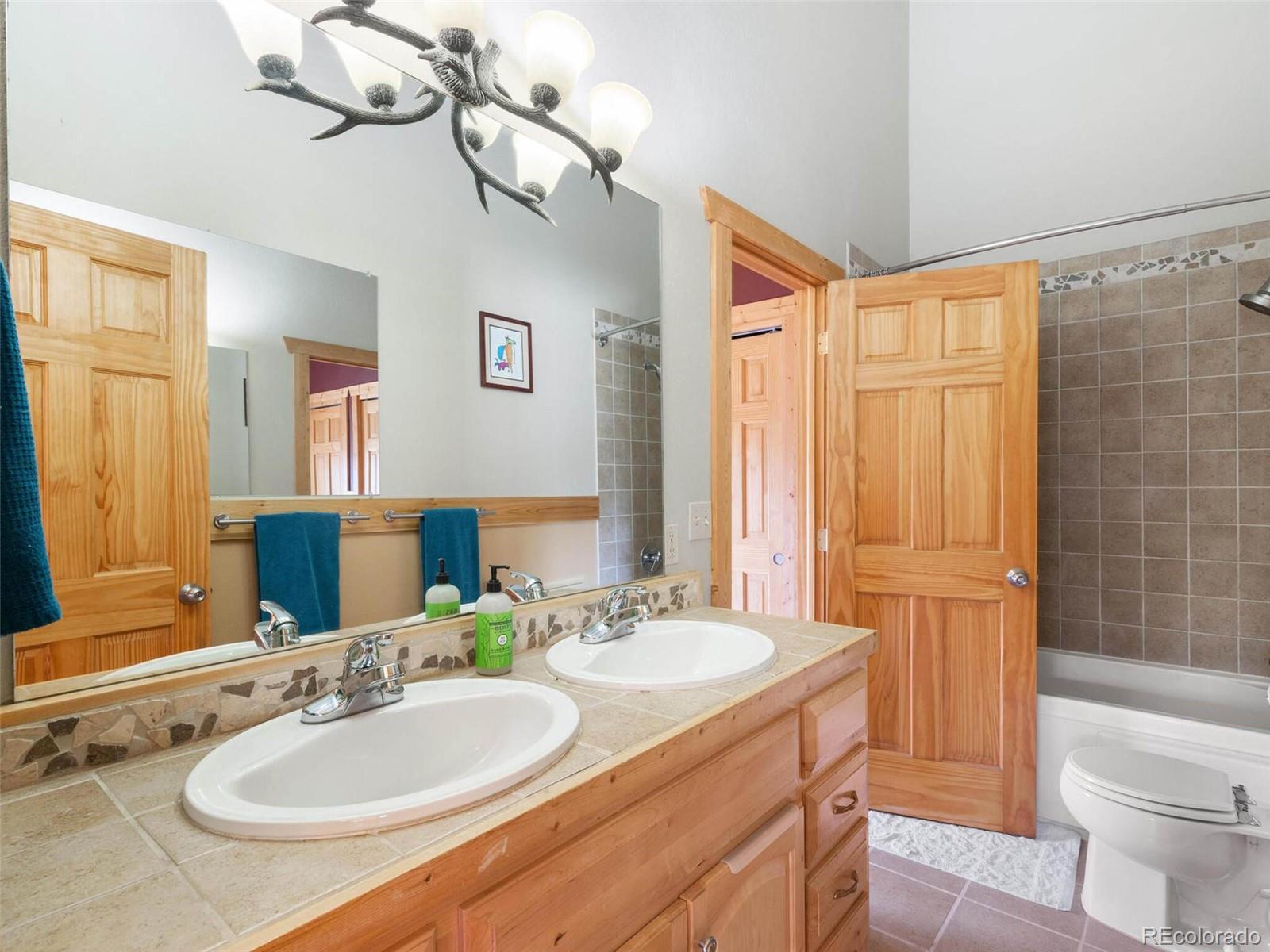 603 Old State Road Bailey, CO 80421 - Photo 26 of 40 a bathroom with a granite countertop sink a toilet a mirror and shower