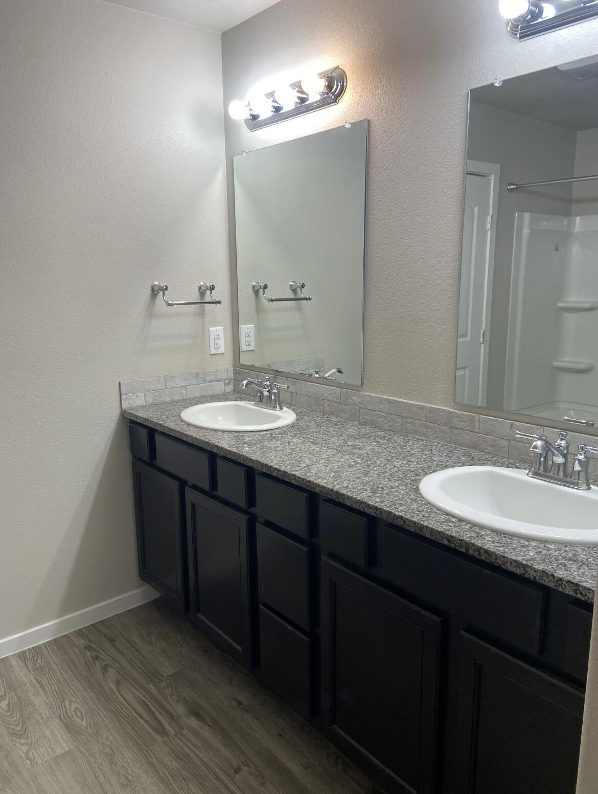 14413 Avenue X, Unit 12 Lubbock, TX 79423 - Photo 4 of 7 a bathroom with a granite countertop sink a large mirror and a