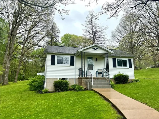 a front view of house with a garden and trees
