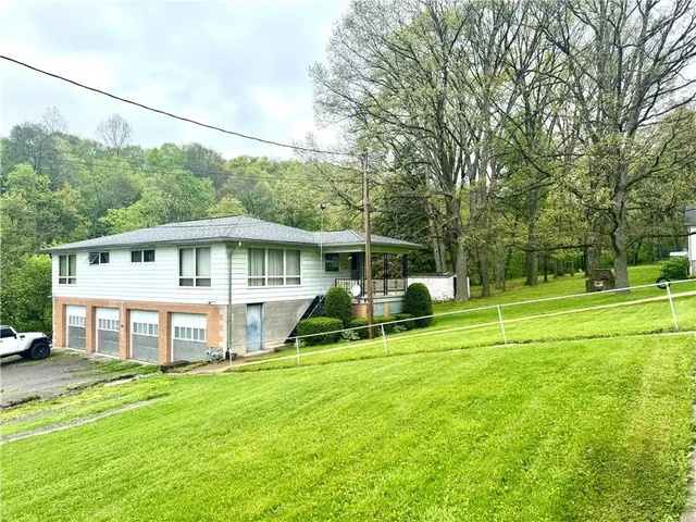 a view of a house with a big yard and large trees