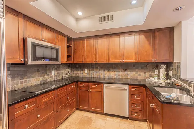 a kitchen with stainless steel appliances granite countertop wooden cabinets a stove top oven a sink and dishwasher