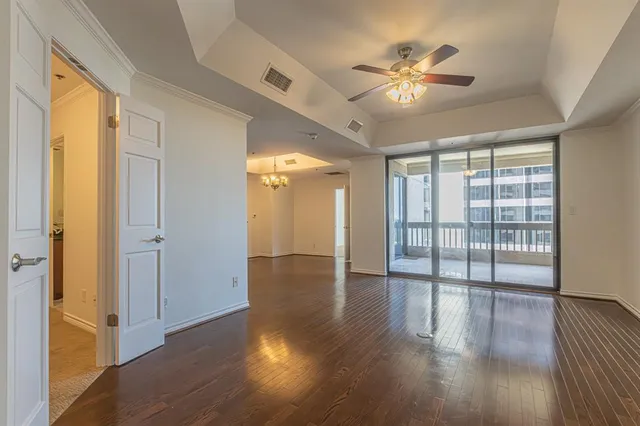 a view of an empty room with wooden floor and a kitchen