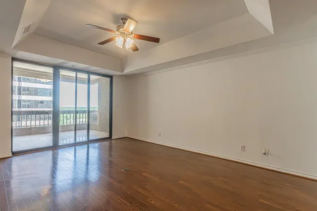 an empty room with wooden floor and a kitchen