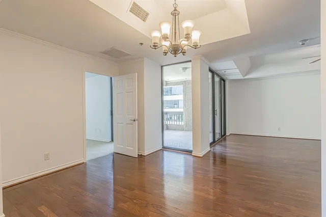 a view of a hallway with wooden floor and a chandelier