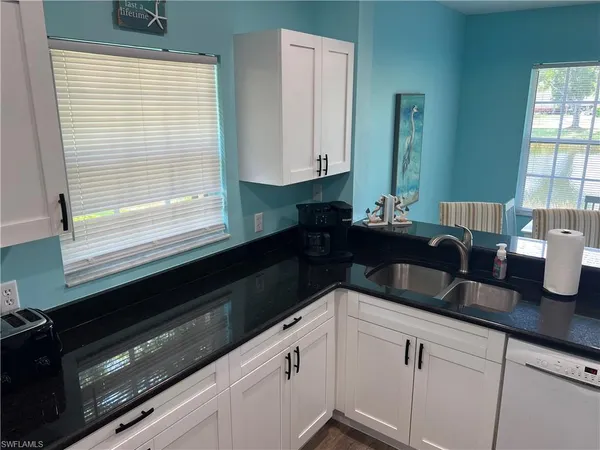 a kitchen with granite countertop a sink and white cabinets