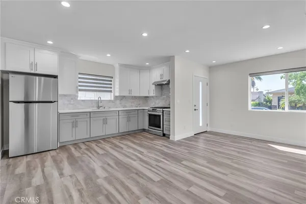 a kitchen with stainless steel appliances granite countertop a refrigerator sink and white cabinets