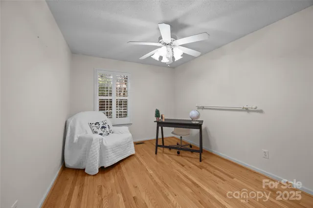 a view of empty room with wooden floor and chandelier