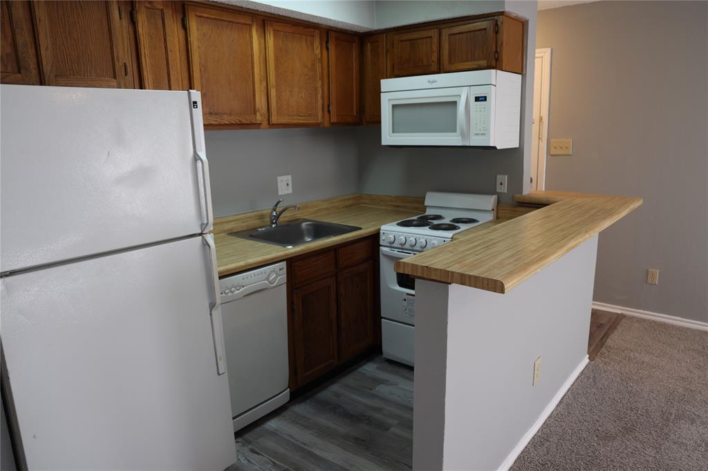 9805 Walnut Street, Unit 305C Dallas, TX 75243 - Photo 11 of 19 a kitchen with stainless steel appliances granite countertop a refrigerator a stove a sink and a microwave