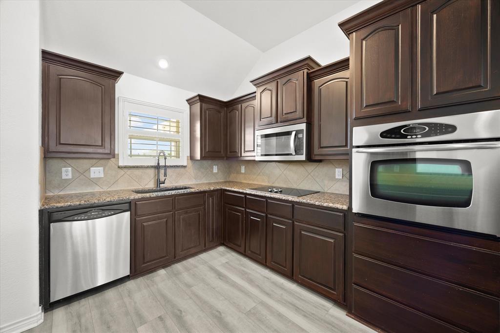 528 Hubbard Circle Nevada, TX 75173 - Photo 14 of 38 a kitchen with stainless steel appliances granite countertop a sink stove and microwave