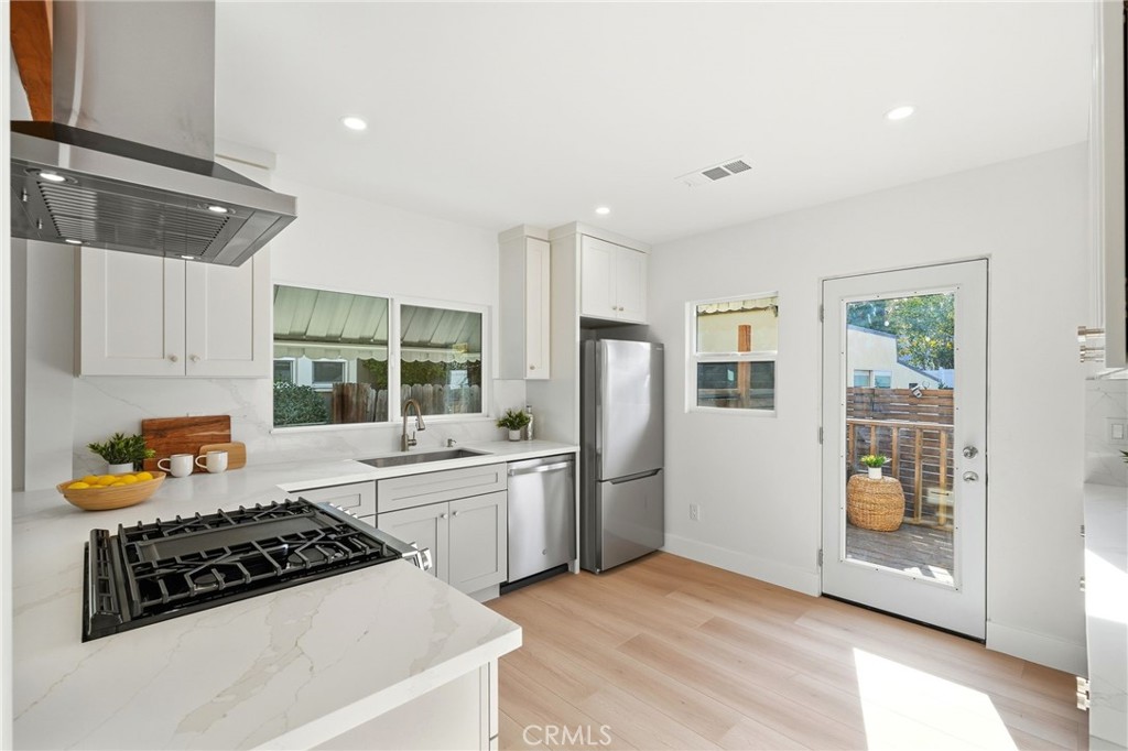 829 North Valley Street Burbank, CA 91505 - Photo 18 of 58 a kitchen with stainless steel appliances granite countertop a refrigerator a stove a sink and a dining table with wooden floor