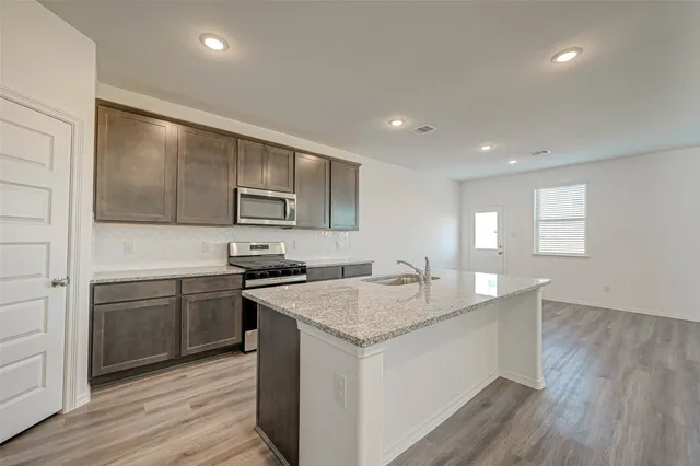 a kitchen with stainless steel appliances granite countertop a sink stove and refrigerator